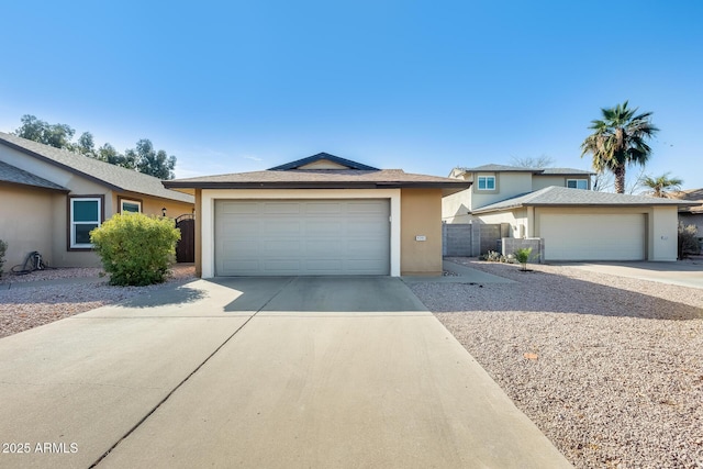 view of front of home featuring stucco siding, a garage, and fence