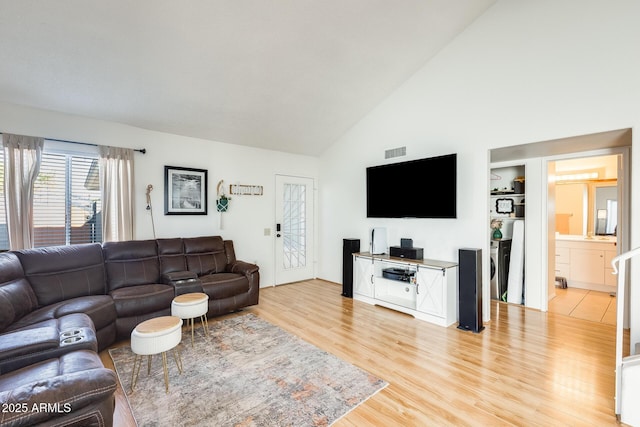 living room featuring visible vents, high vaulted ceiling, and light wood-style flooring