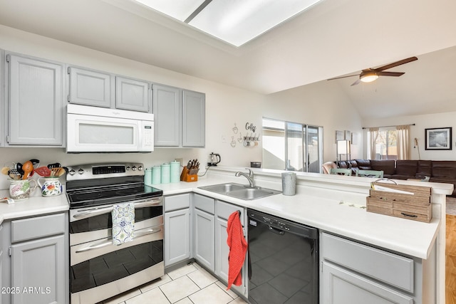 kitchen with white microwave, a peninsula, range with two ovens, a sink, and black dishwasher