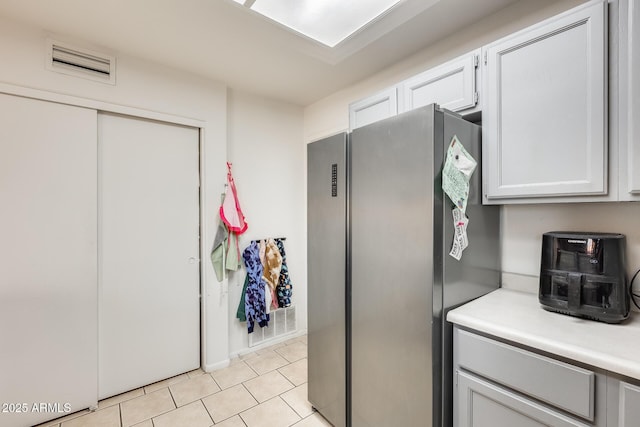 kitchen featuring light tile patterned floors, visible vents, light countertops, and freestanding refrigerator