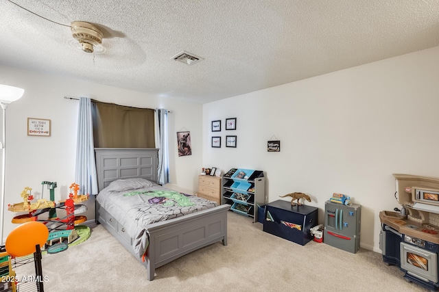 bedroom with visible vents, light carpet, a textured ceiling, and ceiling fan