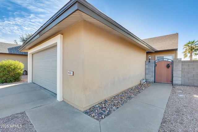 exterior space with an outdoor structure, a gate, roof with shingles, and stucco siding