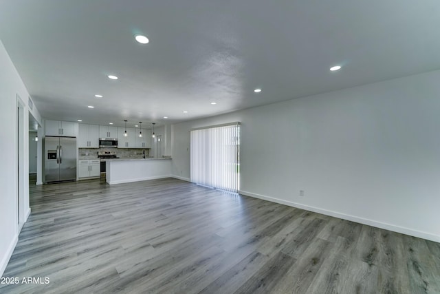 unfurnished living room featuring recessed lighting, light wood finished floors, and baseboards