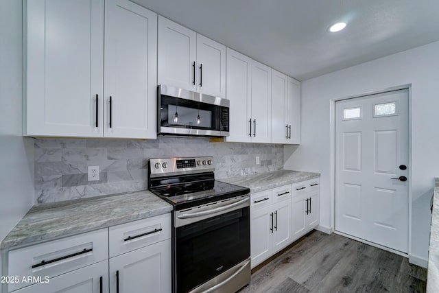 kitchen featuring appliances with stainless steel finishes, white cabinetry, dark wood-style floors, backsplash, and recessed lighting