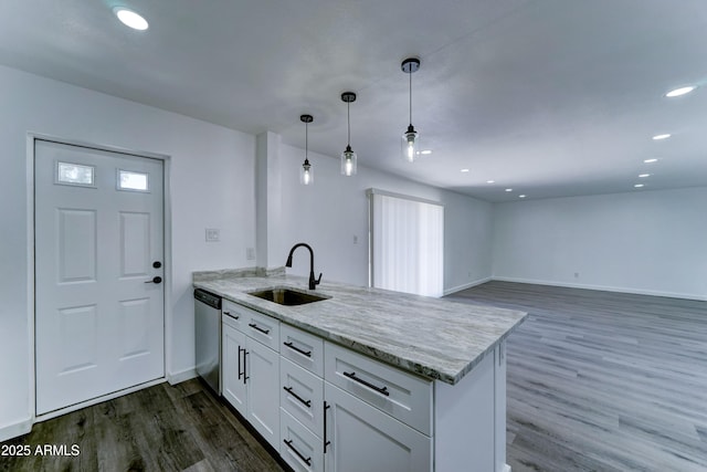 kitchen with a peninsula, a sink, stainless steel dishwasher, white cabinets, and dark wood-style flooring