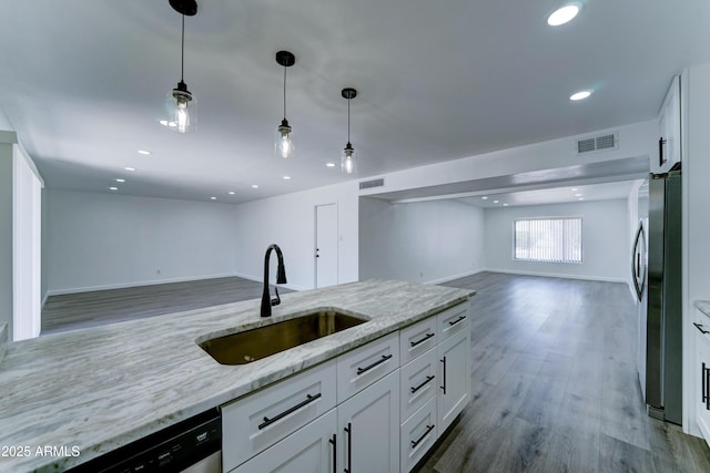kitchen featuring a sink, open floor plan, freestanding refrigerator, dishwashing machine, and white cabinetry