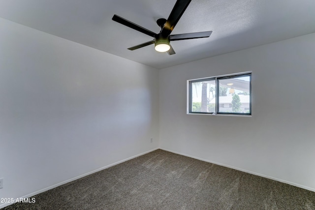 empty room with dark colored carpet, ceiling fan, and baseboards