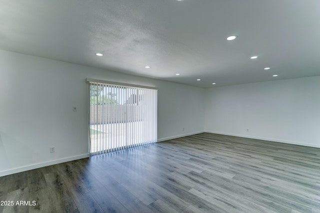 unfurnished room with recessed lighting, wood finished floors, and baseboards