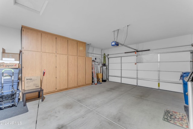 garage with electric panel, a garage door opener, and gas water heater