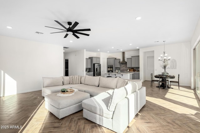 living room featuring ceiling fan with notable chandelier and light parquet floors