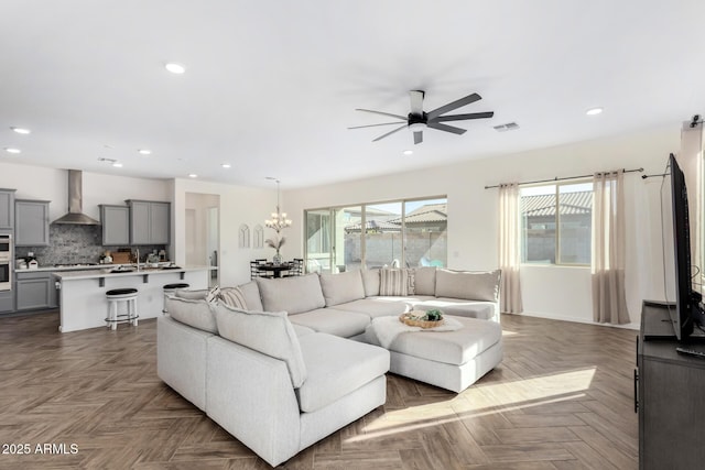 living room featuring dark parquet flooring and ceiling fan with notable chandelier