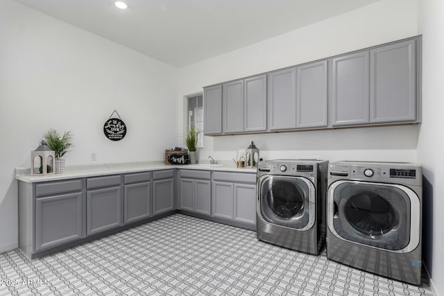 washroom with cabinets, washer and dryer, and sink