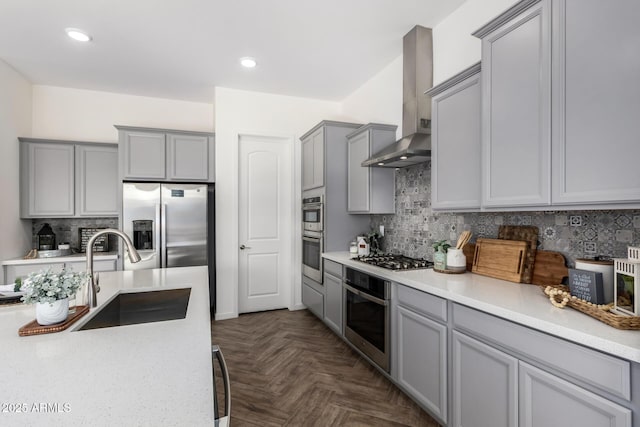 kitchen featuring sink, stainless steel appliances, tasteful backsplash, dark parquet floors, and wall chimney exhaust hood