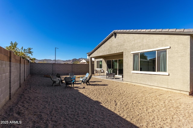 back of house featuring a patio, a mountain view, and a fire pit