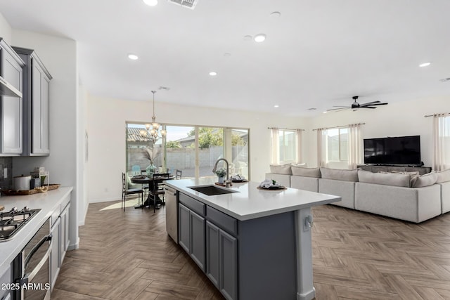 kitchen featuring a kitchen island with sink, sink, parquet flooring, and gray cabinets