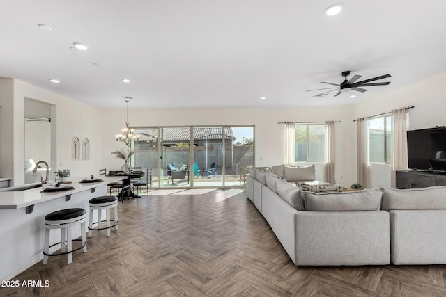 living room featuring parquet flooring, sink, and ceiling fan with notable chandelier