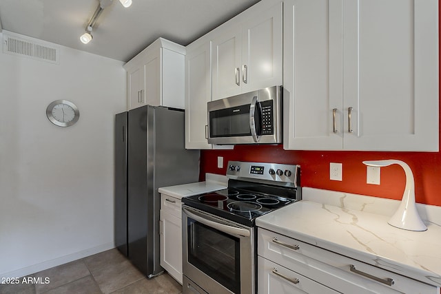 kitchen with visible vents, light stone countertops, appliances with stainless steel finishes, light tile patterned flooring, and white cabinets