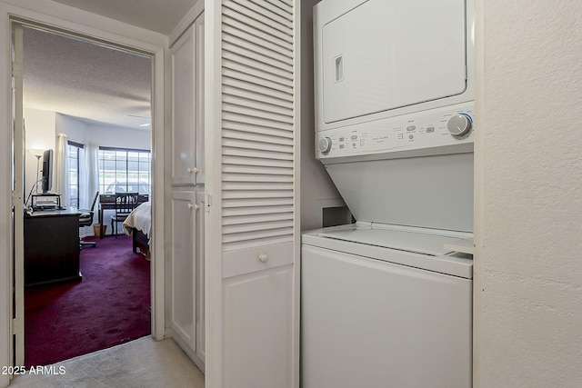 clothes washing area featuring carpet floors, stacked washer and dryer, laundry area, a textured wall, and a textured ceiling