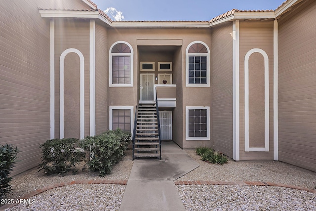 view of exterior entry with stucco siding and a tile roof