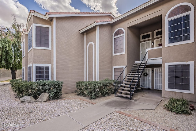 view of exterior entry with a tiled roof and stucco siding