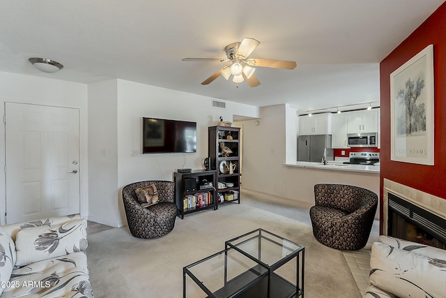 living room featuring visible vents, light colored carpet, a fireplace, and a ceiling fan