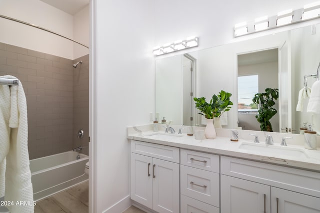 bathroom with hardwood / wood-style flooring, tiled shower / bath combo, and vanity