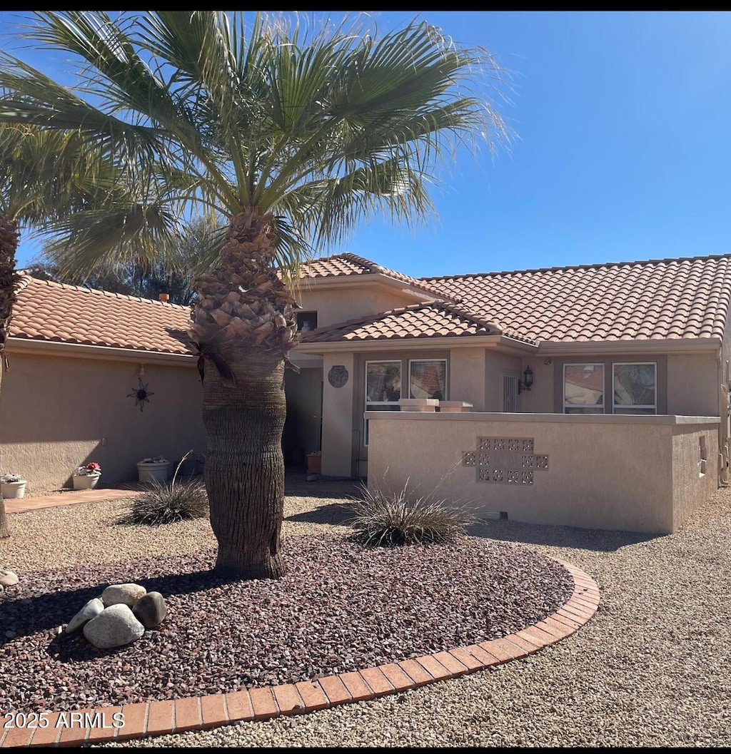 view of front of house with stucco siding, fence, and a tiled roof