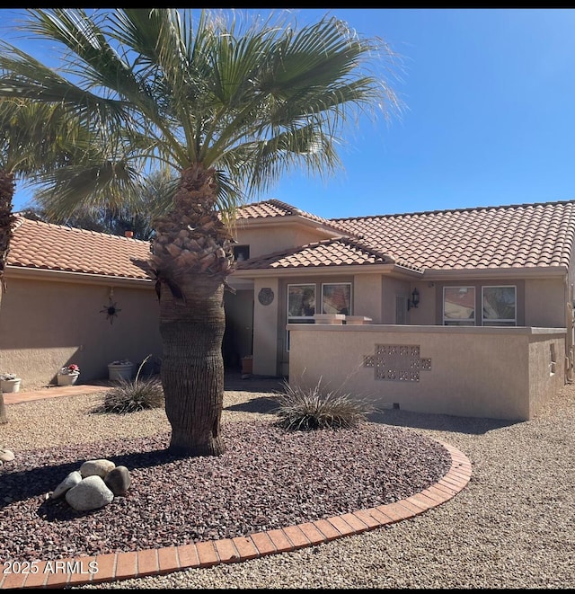 view of front of house with stucco siding, fence, and a tiled roof