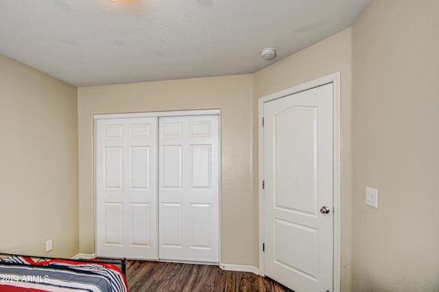 bedroom with a closet, dark hardwood / wood-style floors, and a textured ceiling