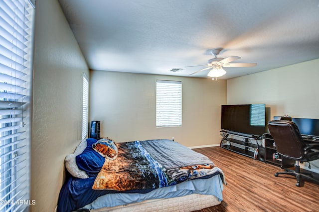 bedroom with ceiling fan, hardwood / wood-style flooring, and a textured ceiling