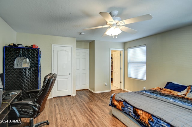 bedroom with a textured ceiling, wood-type flooring, and ceiling fan