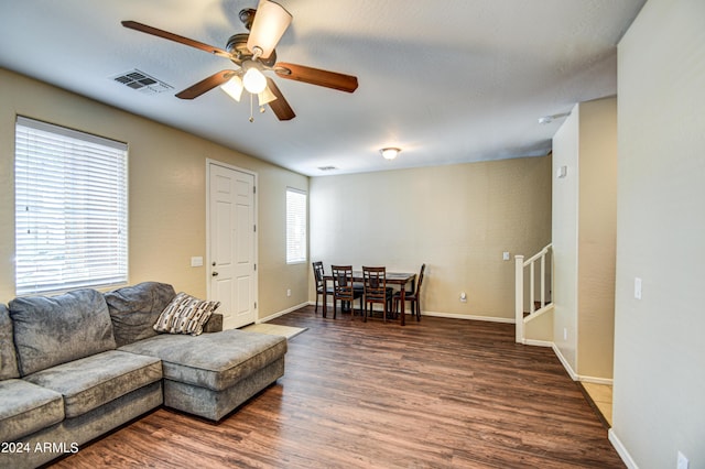 living room featuring a healthy amount of sunlight, dark wood-type flooring, and ceiling fan