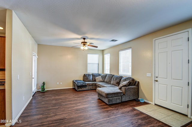 living room featuring ceiling fan, a textured ceiling, and dark hardwood / wood-style flooring