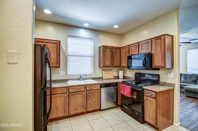 kitchen with sink, light tile patterned floors, and black appliances