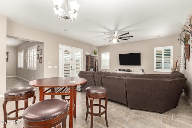 living room with french doors and ceiling fan with notable chandelier