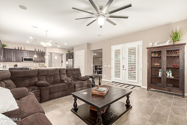 living room featuring ceiling fan with notable chandelier and french doors