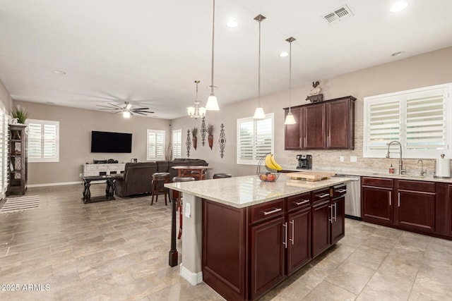 kitchen featuring sink, a breakfast bar, a center island, decorative light fixtures, and stainless steel dishwasher