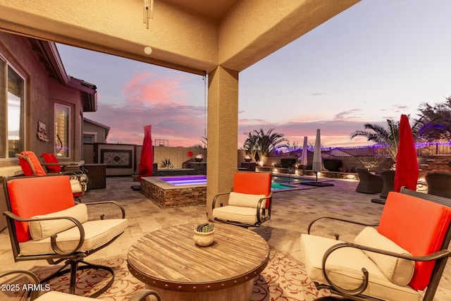 patio terrace at dusk featuring a swimming pool with hot tub