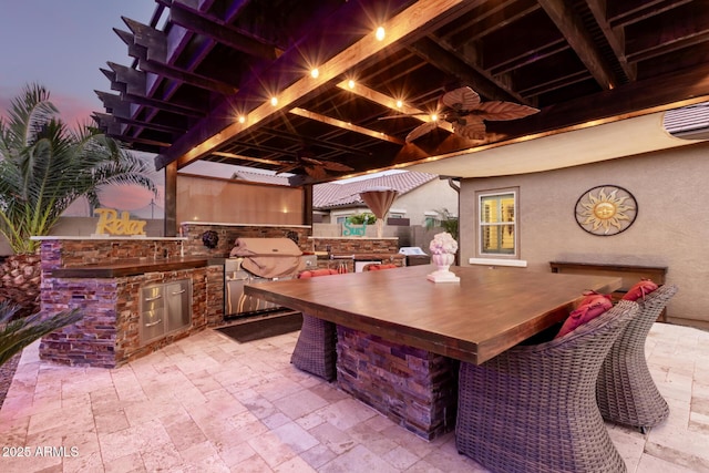 patio terrace at dusk with a bar and area for grilling