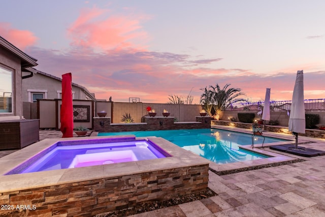 pool at dusk with an in ground hot tub