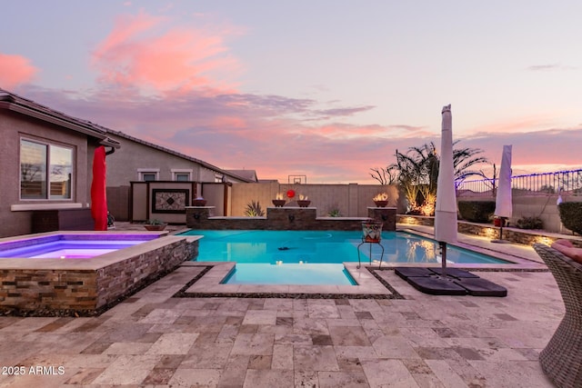 pool at dusk featuring an in ground hot tub and a patio area