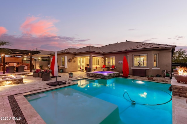 pool at dusk featuring area for grilling, a fire pit, a patio area, and an in ground hot tub