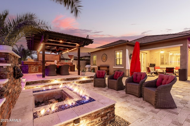 exterior space featuring exterior kitchen, a patio, and an outdoor living space with a fire pit