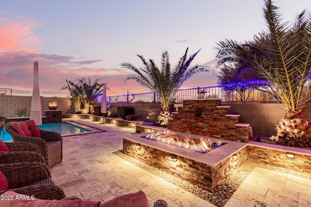 pool at dusk featuring a fire pit and a patio area