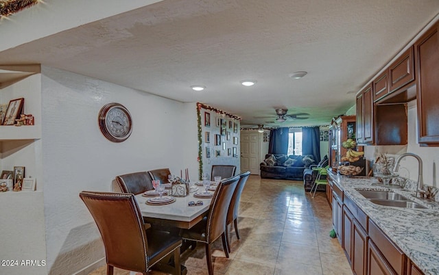 dining area with ceiling fan, sink, light tile patterned floors, and a textured ceiling