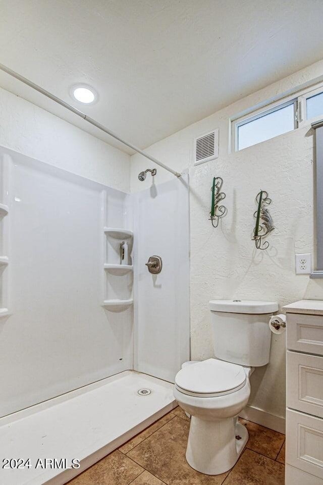 bathroom with tile patterned floors, vanity, toilet, and a shower