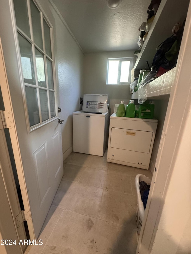 laundry area featuring independent washer and dryer, a textured ceiling, and light tile patterned flooring