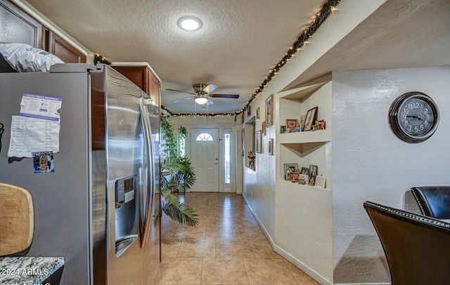 kitchen featuring ceiling fan, stainless steel fridge, light tile patterned floors, and a textured ceiling