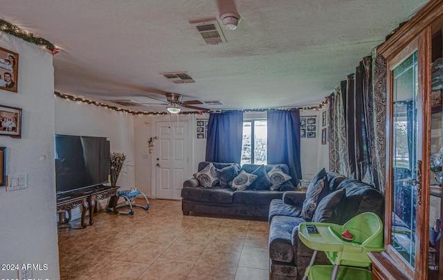 living room featuring a textured ceiling, ceiling fan, and light tile patterned flooring