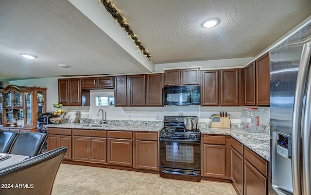 kitchen with sink, rail lighting, light stone counters, a textured ceiling, and black appliances